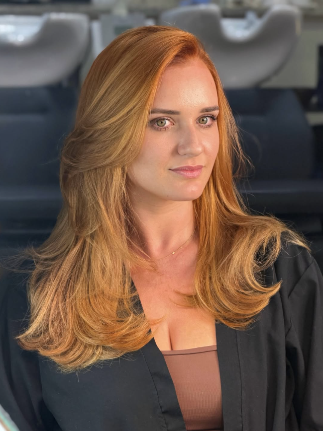 Cliente ruiva com cabelo vibrante e saudável após coloração e tratamento